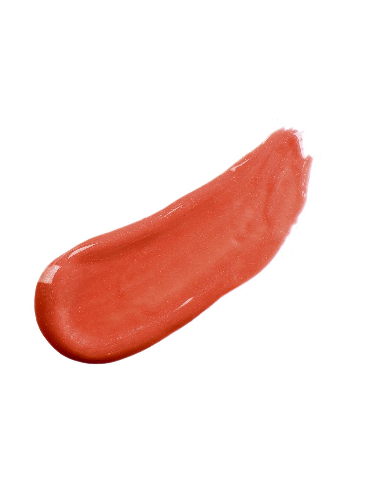 Ein Pinselstrich von korallenrotem Lippenstift auf weißem Hintergrund.