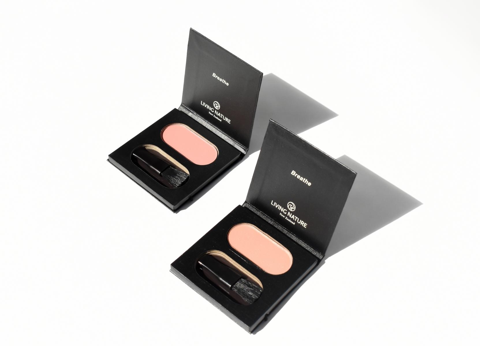 Zwei geöffnete Make-up-Paletten mit Rouge und Pinsel auf weißem Hintergrund.