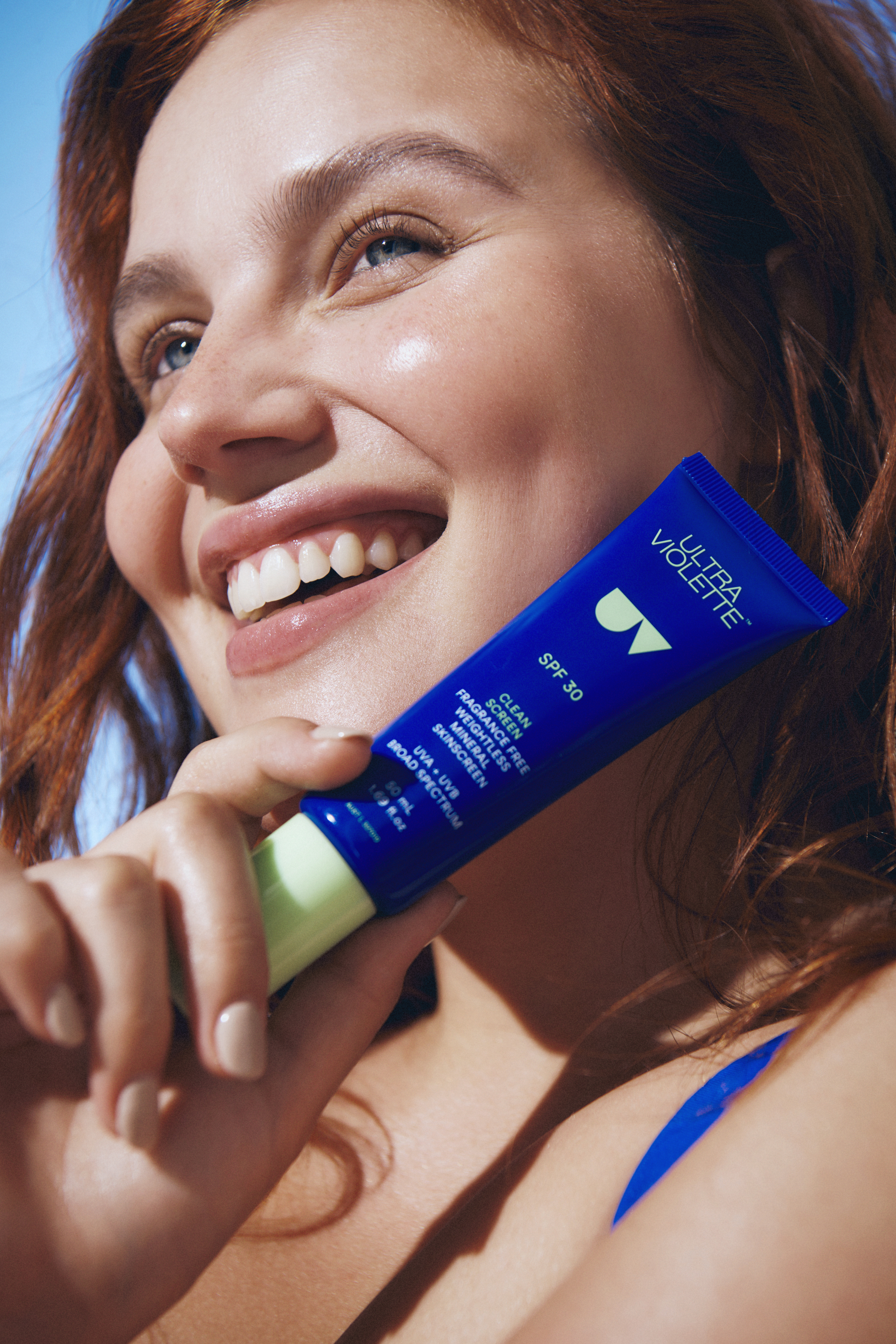 Frau hält Ultra Violette SPF 30 Creme, lächelt in die Kamera.