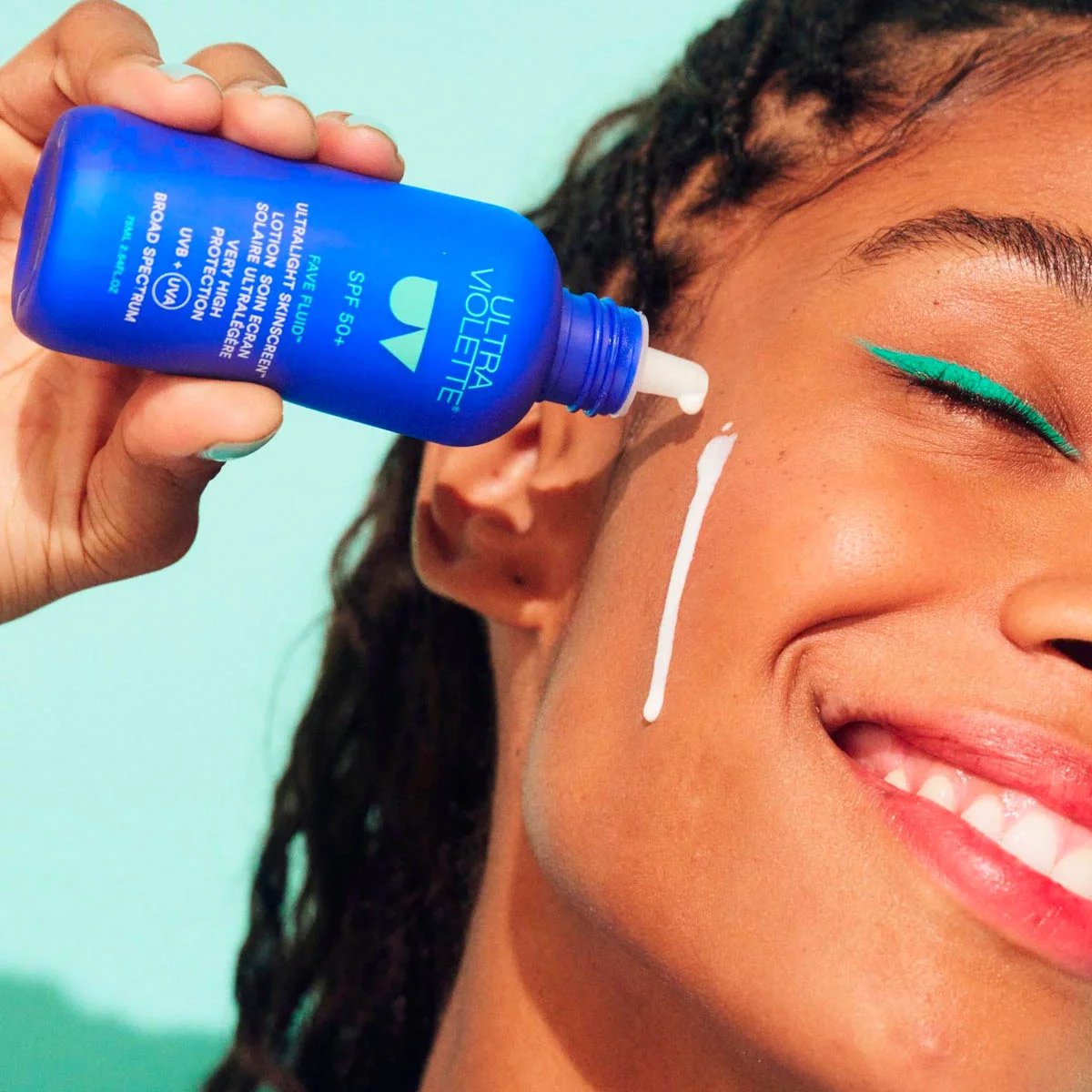 Frau trägt ULTRA VIOLETTE Fave Fluid SPF 50+ Sonnencreme auf ihr Gesicht auf.