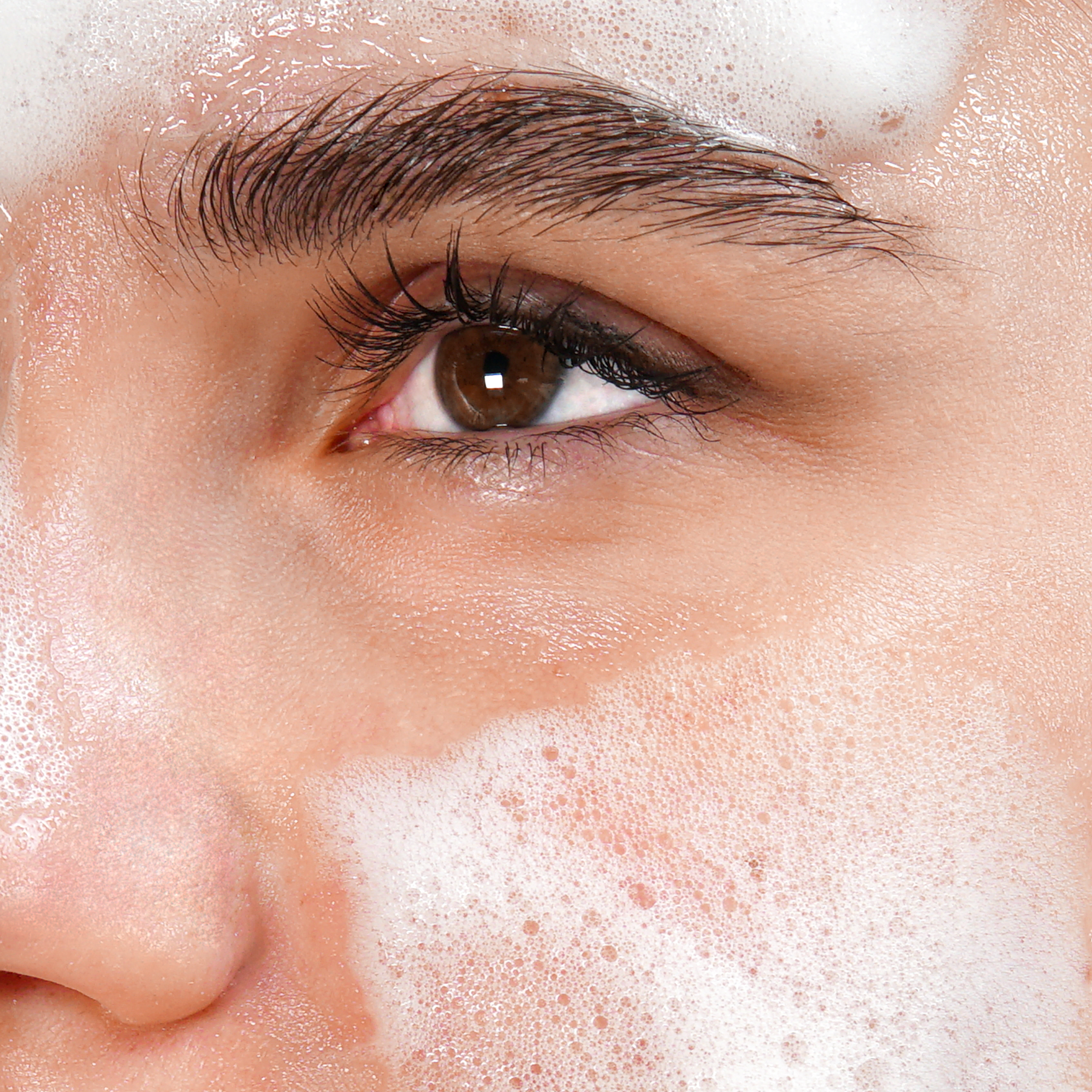 Nahaufnahme eines Gesichts mit Schaumreiniger auf der Haut.