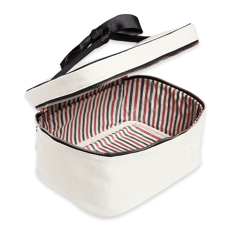 Geöffnete weiße Kosmetiktasche mit gestreiftem Innenfutter und schwarzem Reißverschluss.